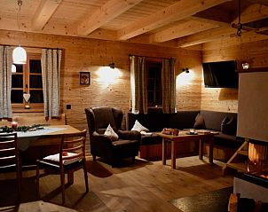 Sfeervolle woonkamer van Vakantiehuis in Geiersthal/Altnuberg, Beieren, Duitsland, met uitnodigende open haard en houten plafondbalken.