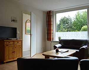 Gezellige woonkamer in Appartementen-Annema, Nes, Ameland met comfortabele zithoek en uitzicht op de groene omgeving van de Waddeneilanden.