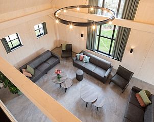 Bovenaanzicht van de woonkamer in de Schuur van Driehoekshoeve, Kasterlee, met moderne meubels en hoge plafonds.