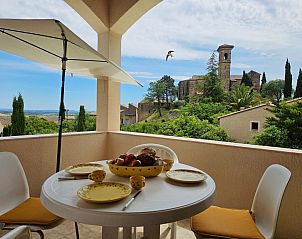 Terras van Sourire du Soleil vakantiehuis in Montouliers, Languedoc, biedt een schilderachtig uitzicht op de kerk en het omliggende landschap.