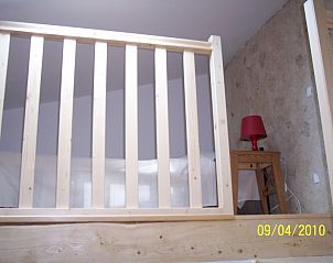 Charmante slaapkamer in Figuier vakantiehuis, Aiguines, Provence, met houten balustrade en sfeervolle stenen muur.
