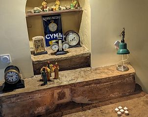 Charmante inrichting van Vakantiehuisje in Prudhomat, met klassieke klokken en warme stenen accenten in de woonkamer.