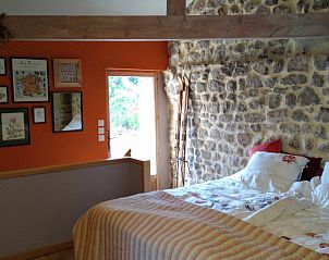 Rustieke slaapkamer van Source bien-aime vakantiehuis in Chanac, Rhone-Alphes, met stenen muren en warme ambiance.