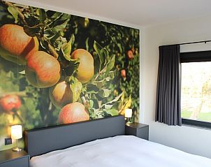 Slaapkamer in Etsrike vakantiewoning, Halen, Limburg met fruitige muurschildering en uitzicht op de tuin.