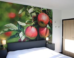 Gezellige slaapkamer in Etsrike vakantiehuis in Halen, Limburg met appelmuurschildering en natuurlijke lichtinval.