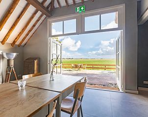 Eetkamer in Vakantiehuisje in Piaam met uitzicht op de tuin en velden, ideaal voor een ontspannen maaltijd aan de Friese meren.
