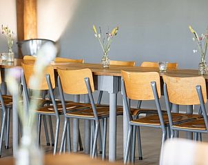 Lange houten tafel in Vakantiehuisje in Piaam, gedecoreerd met bloemen, perfect voor groepsmaaltijden aan het IJsselmeer.