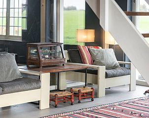 Zithoek bij de trap in Vakantiehuisje in Piaam met uitzicht op groene velden, ideaal voor een rustige middag aan het IJsselmeer.