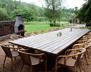 Buitenruimte met grote tafel en barbecue bij Maison Polleur, vakantiehuis in de Ardennen, voor gezellig samenzijn.