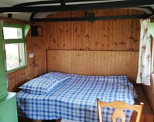 Gezellige slaapkamer in PIPOWAGEN vakantiehuis, Wodecq, Henegouwen, met houten interieur en comfortabel bed.
