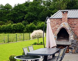 Terrace of Cottage in Sautin with stone barbecue and views of lush nature in Hainaut, Belgium.