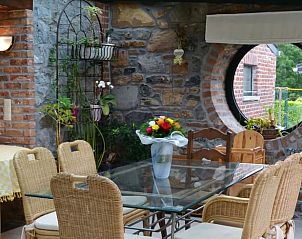 Detail of the dining area in Holiday home in Sautin with flowers and decorative stone wall, Hainaut, Belgium.