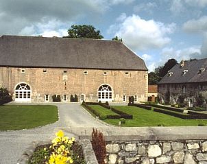 Buitenkant van Ferme de l'Abbaye de Moulins, een vakantiehuis in Anhe, Ardennen, met een indrukwekkend stenen gebouw en verzorgde tuinen.