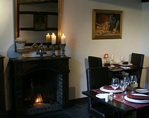 Gezellige eetruimte bij Le Secret du Bois, bed and breakfast in Gedinne, Ardennen, met open haard en sfeervolle kaarsen.