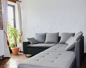 Comfortabele zithoek in Les Lilas vakantiehuis, Sart-En-Fagne, Ardennen, met grijze bank en veel licht.