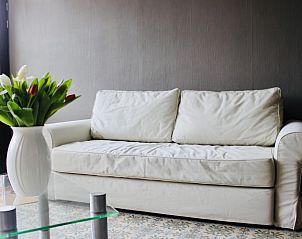 Lichte woonkamer in Les Lilas vakantiehuis, Sart-En-Fagne, Ardennen, met witte bank en glazen tafel.