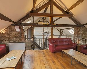 Gezellige woonkamer in Les Trois Sangliers vakantiehuis, Chanly, Ardennen, met houten balken en leren meubels.