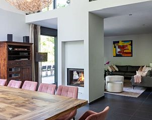 Open eetruimte en woonkamer in La Roche Durbuy vakantiehuis met grote ramen en open haard.