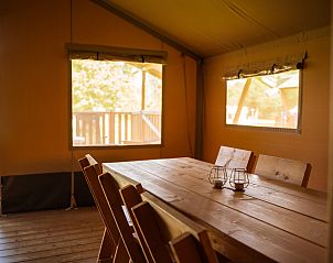 Gezellige binnenruimte van Safaritent + sanitair in Tintigny, Ardennen, Belgi met houten eettafel en uitzicht op de natuur.
