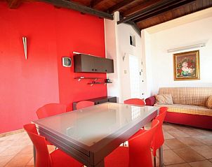 Stijlvolle woonkamer van Villa Verdemare in Noto, Sicili. Vakantiehuis met rode decoratie en comfortabele zithoek.