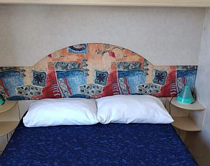 Gezellige slaapruimte in Toscachalets, Viareggio, Toscane met uniek design hoofdbord en zachte kussens.