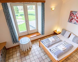 Comfortabele slaapkamer in Berismenil Gardens, La Roche-en-Ardenne, met toegang tot een balkon en uitzicht op de tuin in de Ardennen.