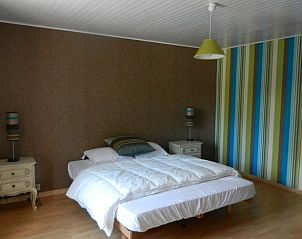 Sfeervolle slaapkamer in Huisje in Anloy, vakantiehuis in de Ardennen, Belgi, met een knus tweepersoonsbed en kleurrijke accentmuur.