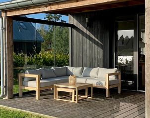 Loungehoek op veranda van Vakantiehuisje in Sint Nicolaasga, met uitzicht op de groene omgeving van de Friese meren.