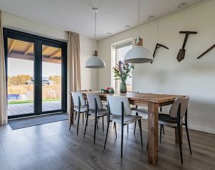 Eetkamer in Vakantiehuisje in Sint Nicolaasga, met houten tafel en uitzicht op de Friese meren.