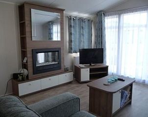 Lichte woonkamer met open haard in chaletmiddelkerke, stacaravan aan de Belgische kust.