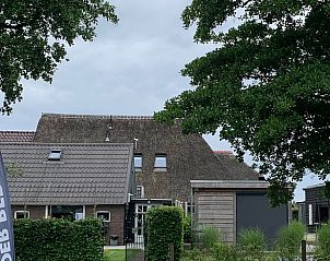 Buitenkant van Vakantiehuis in Beilen, Midden Drenthe met rieten dak en groene omgeving.