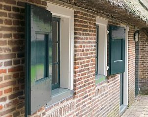 Traditionele groene luiken van vakantiehuis Orvelte, Midden Drenthe met bakstenen muur.