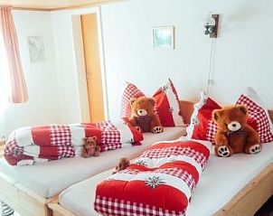 Knusse slaapruimte in Huschen, Winikon, Zwitserland, met sfeervolle houten elementen en uitnodigende bedden.