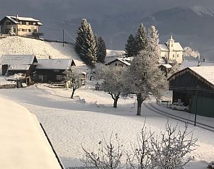 Rustiek winterlandschap bij Huisje in Vignogn, vakantiehuis in Graubunden, Zwitserland, met besneeuwde daken en bomen.