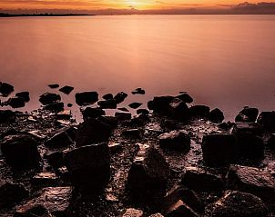 Huisje in Paesens, rustgevend uitzicht op de Friese zee bij zonsondergang.