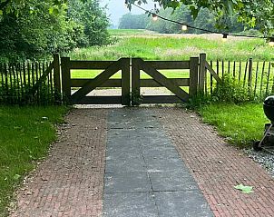 Charmante toegangspoort naar Vakantiehuisje in Oldeholtpade, omgeven door natuur op het Friese platteland in Friesland.