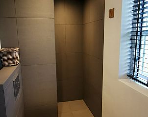 Strakke douche in Huisje in Kootstertille, vakantiehuis in Friesland, met moderne tegels en natuurlijke lichtinval.