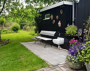 Rustieke buitenruimte bij Vakantiehuis in Kootstertille, Friesland, met bankje en bloemen.
