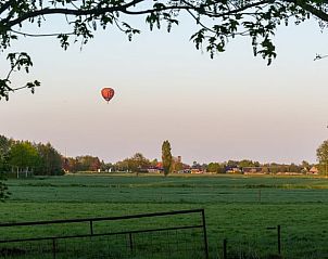 Uitzicht op het Friese platteland bij Huisje in Echten, een vakantiehuis in Friesland, met een luchtballon in de serene ochtendlucht.