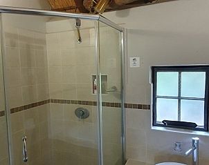 Badkamer in Ons Blyplek, Marloth Park, Kruger Park, met glazen douche en charmant rieten dak, ideaal voor een ontspannen verblijf.