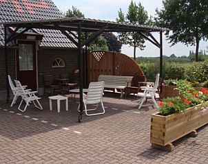 Terras bij De Bonenkamp vakantiehuis in Echteld met comfortabele zitplaatsen en bloemen in Rivierengebied.