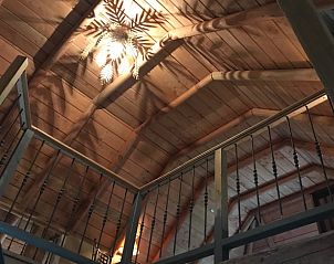 Houten plafond en sfeervolle verlichting in Huisje in Oene, vakantiehuis op de Veluwe, Gelderland, voor een rustieke ambiance.