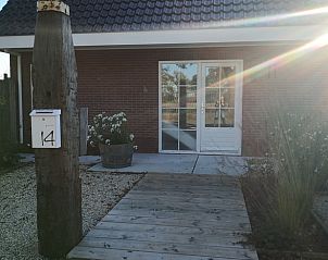 Ingang van Vakantiehuis in Opende, Zuidwest Groningen met houten pad en bloeiende planten