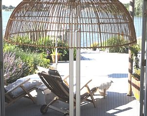 Uitzicht op terras en meer vanuit Vakantiehuis in Opende, Zuidwest Groningen met hanglamp