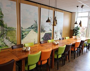 Gezellige eetruimte in de Heidehof vakantiehuis in Schaijk met kleurrijke stoelen en kunst aan de muur.