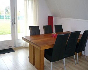 Eetruimte in Vakantiewaddenzee.nl vakantiehuis, Den Oever, met houten tafel en uitzicht op de tuin.