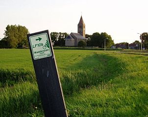Fietspad bij Den Oever met uitzicht op een kerk, in de buurt van Vakantiewaddenzee.nl, Waddenkust.