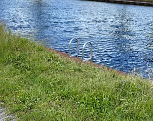 Rustige waterkant met grasveld bij Vakantiehuisje in Landsmeer, Amsterdam Noord-Holland.