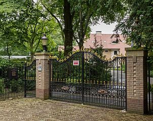 Ingangspoort van Huisje in Laren, vakantiehuis in Laren, Amsterdam eo, Noord-Holland, omringd door groen.