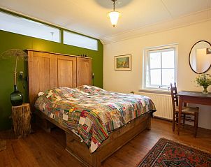 Rustieke slaapkamer in Huisje in Tilligte, vakantiehuis in Twente, Overijssel met houten meubels en kleurrijk beddengoed.